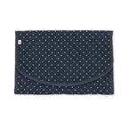 A navy blue quilted baby blanket with a white polka dot pattern, featuring a curved front pocket and a small white tag on the left side, shown flat against a white background.