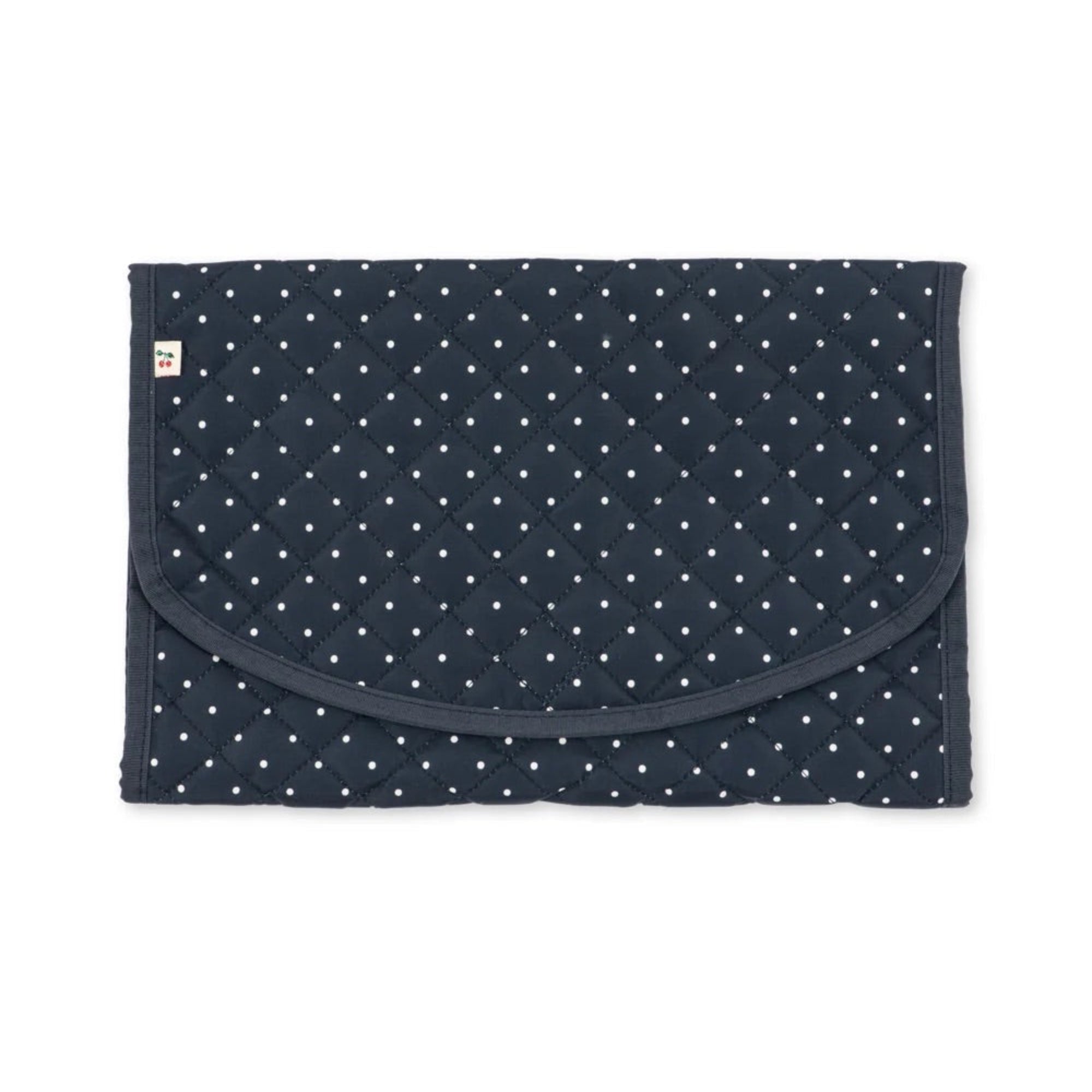 A navy blue quilted baby blanket with a white polka dot pattern, featuring a curved front pocket and a small white tag on the left side, shown flat against a white background.