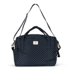 A navy blue fabric bag with a white polka dot pattern, featuring top handles, a detachable shoulder strap, and a small beige brand label on the front.