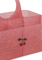 A translucent pink plastic caddy organizer with a white glitter speckle pattern and a small cherry graphic on the front, shown on a white background.
