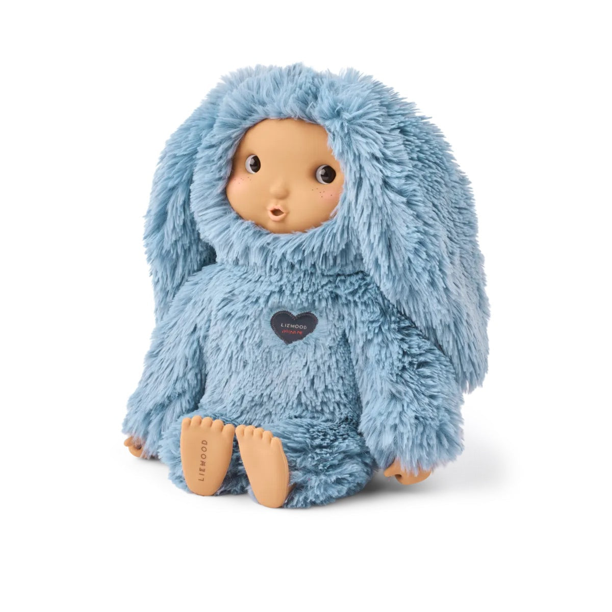 A soft plush doll with a light blue bunny-like hooded outfit, tan skin face and feet, and a small dark heart-shaped chest label, photographed on a clean white background.