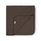 A folded dark brown cotton blanket with a small white brand tag, displayed on a clean white background.