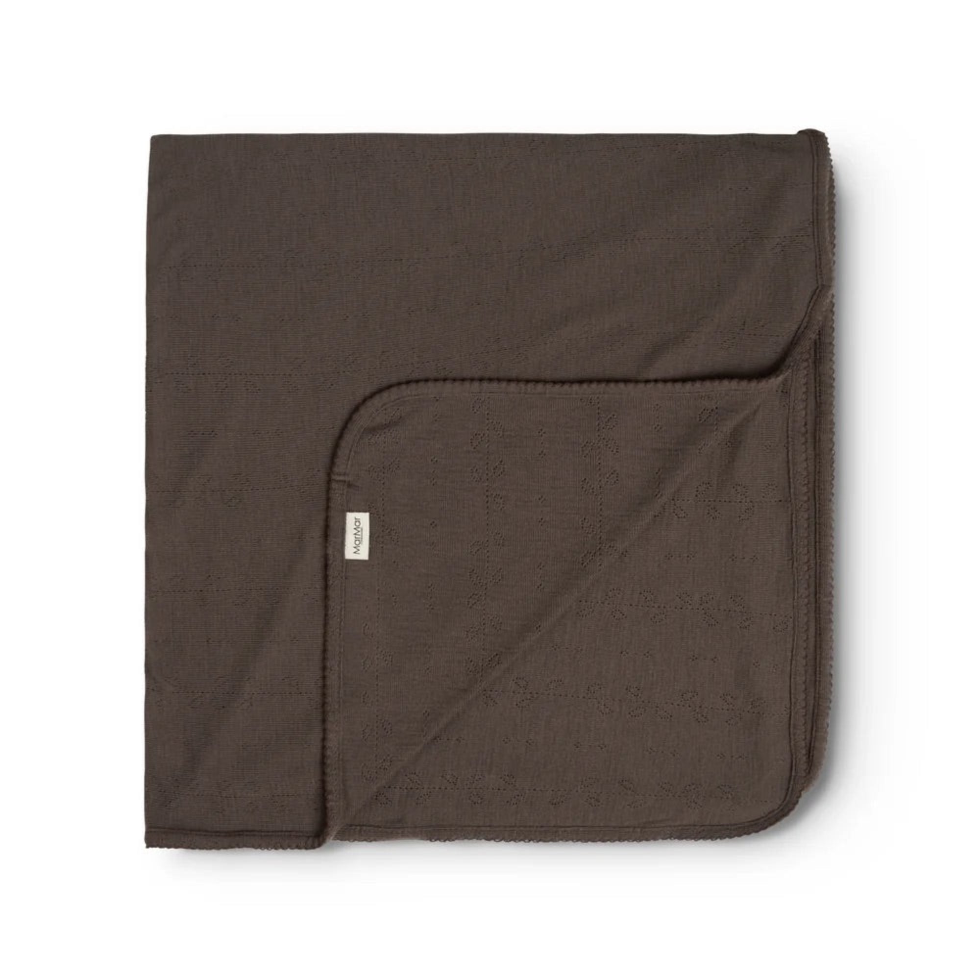 A folded dark brown cotton blanket with a small white brand tag, displayed on a clean white background.