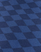A close-up of a blue and navy checkered fabric pattern with a visible woven texture.