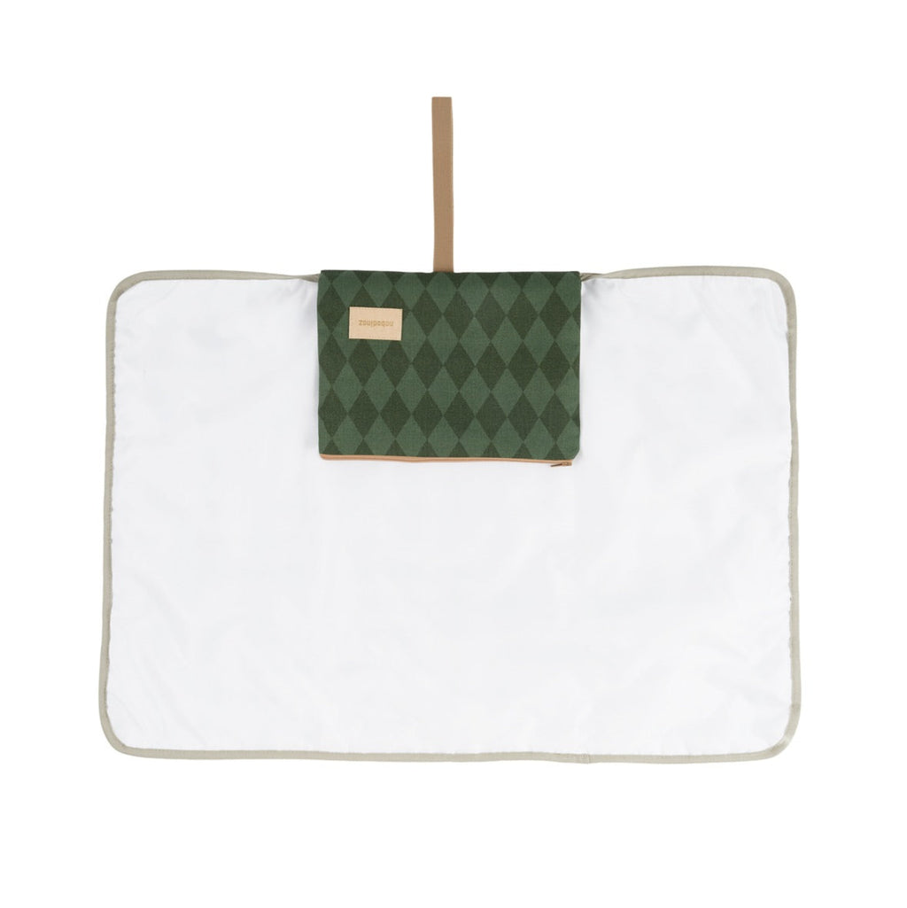 A white rectangular quilted blanket or mat with a light beige border, featuring a green argyle patterned pocket on the front with a tan leather-like label and a matching tan hanging strap.