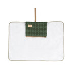 A white rectangular quilted blanket or mat with a light beige border, featuring a green argyle patterned pocket on the front with a tan leather-like label and a matching tan hanging strap.