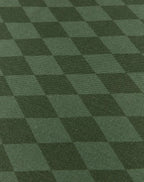 A close-up of a dark green checkered fabric or carpet texture with alternating lighter and darker green squares.