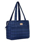 A navy blue quilted duffel bag with a subtle diamond pattern, featuring dual shoulder straps, a zippered main compartment, and a small tan leather brand patch on the front.