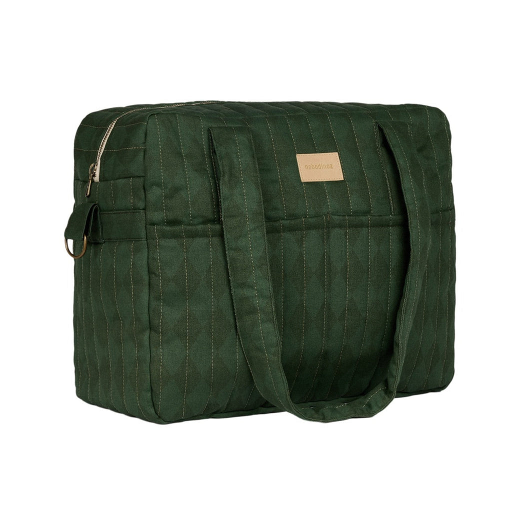 A dark green quilted puffer bag with dual shoulder straps and a small tan leather brand patch on the front, shown against a plain white background.