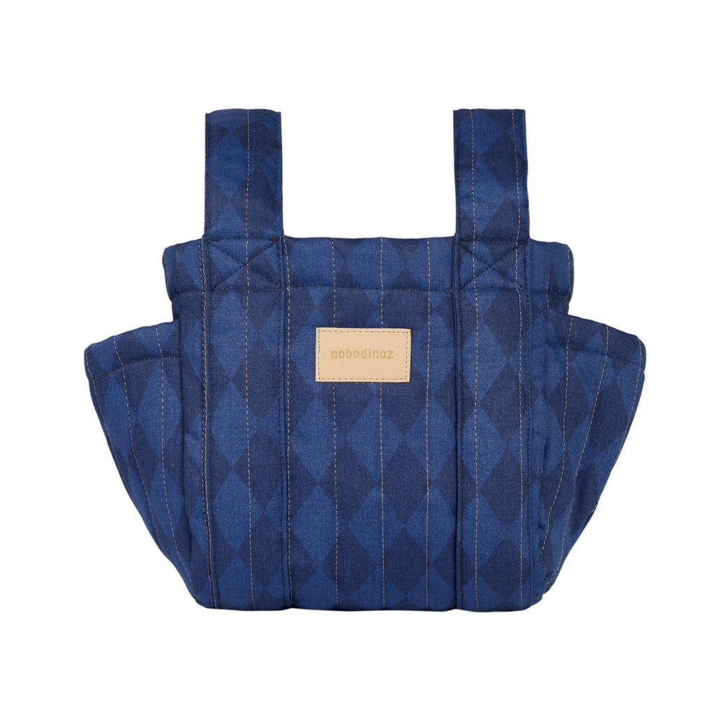 A quilted blue baby carrier bag with a diamond pattern and a tan leather brand patch on the front, shown against a plain white background.