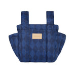 A quilted blue baby carrier bag with a diamond pattern and a tan leather brand patch on the front, shown against a plain white background.