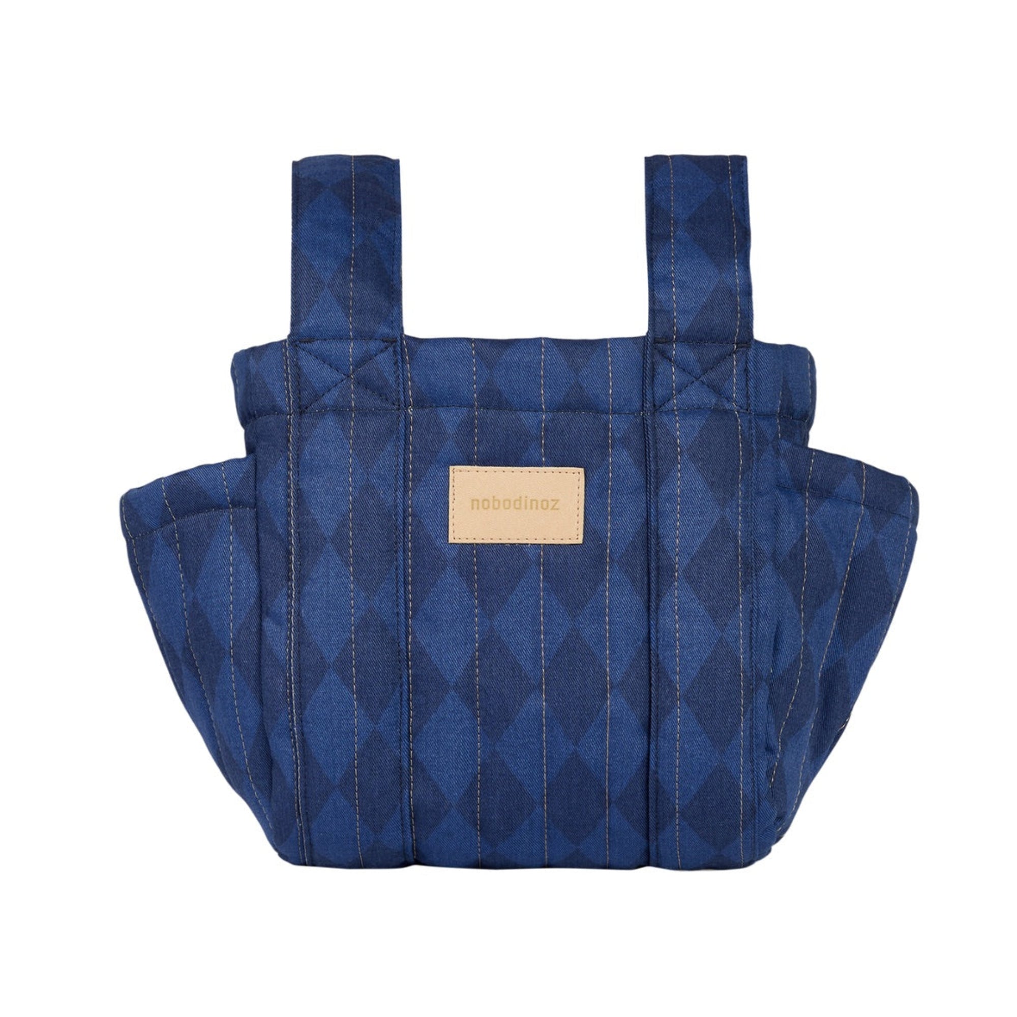 A quilted blue baby carrier bag with a diamond pattern and a tan leather brand patch on the front, shown against a plain white background.