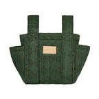 A dark green quilted fabric tote bag with vertical stitching, dual shoulder straps, and a small tan leather brand patch on the front, shown against a plain white background.