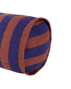 A close-up of a cylindrical bolster pillow with alternating horizontal stripes of rust brown and deep purple, shown on a plain white background.